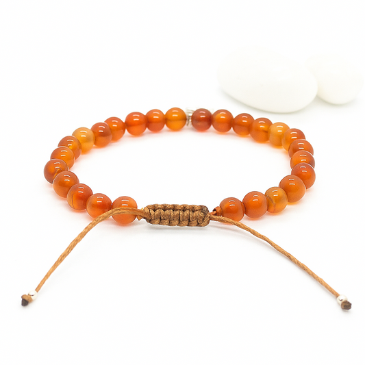 Orange beaded bracelet with a woven closure on a white background